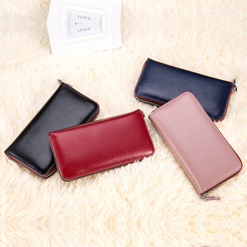 Quatre portefeuilles en cuir grainé noir, rouge, bleu marine et rose sur un tapis moelleux